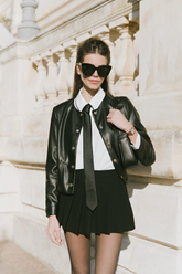 a lady in a white shirt, a black leather coat, and a black skirt